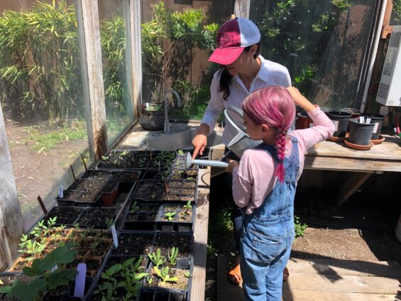 brise and her daughter watering seedlings in the greenhouse