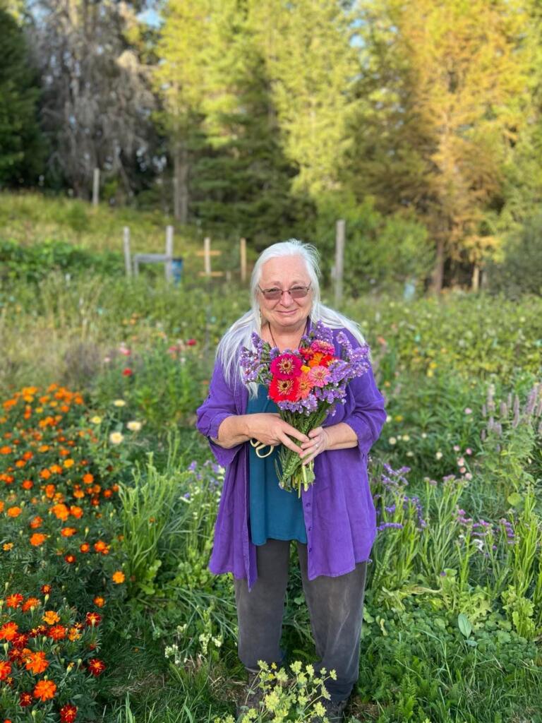 Diane Green of Greentree Naturals Farm standing in her main garden with a bouquet of flowers
