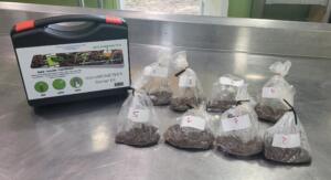 8 bags of soil sit on a metal counter next to a soil testing kit.