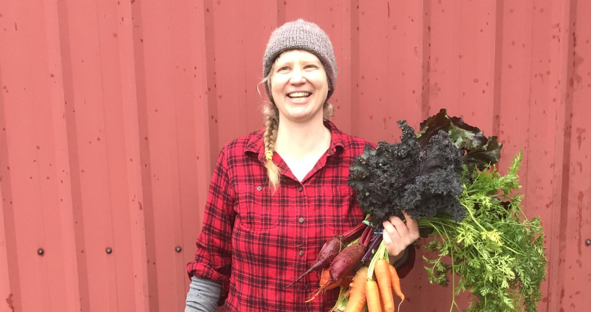 April Thatcher, farmer and OFRF Board President, holding carrots