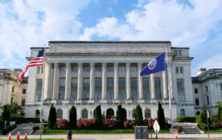 photo of USDA building in Washington DC with a blue and cloudy sky behind it.