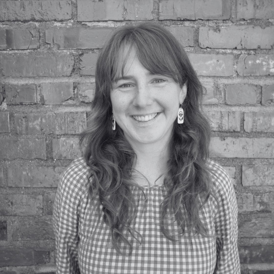 headshot of Annika Sampson in black & white against brick wall