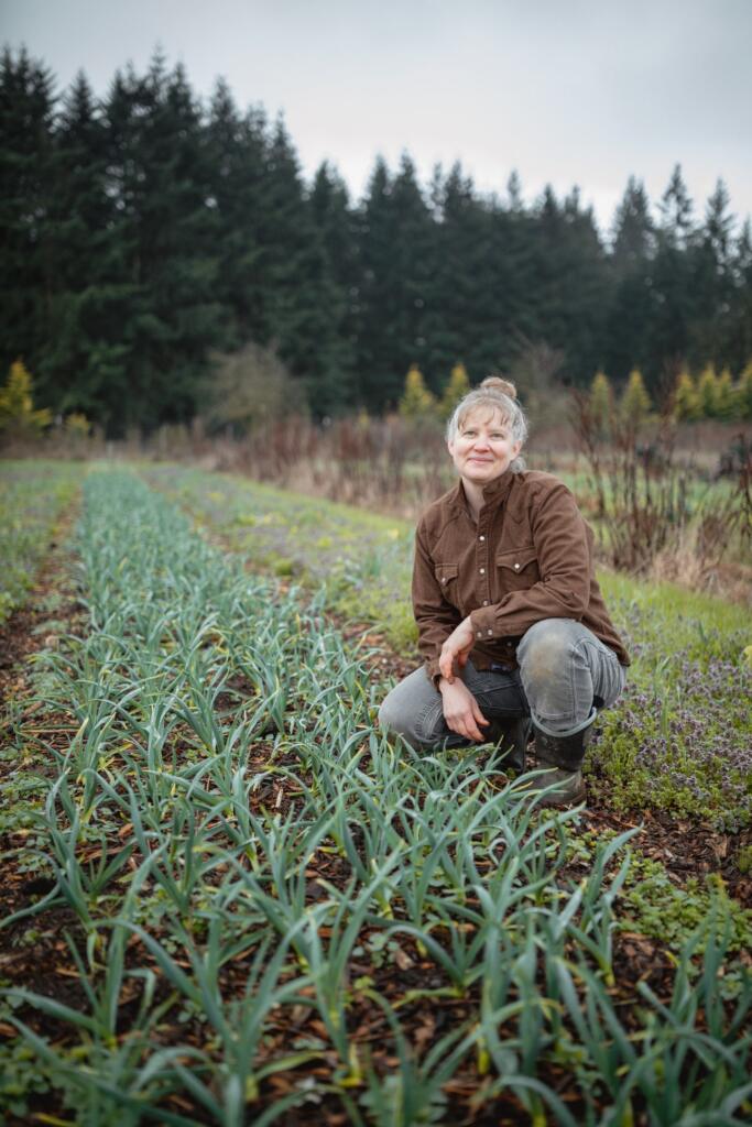 april-thatcher-april-joy-farm-on-the-farm April Jones Thatcher of April Joy Farm kneeling in a field on her farm
