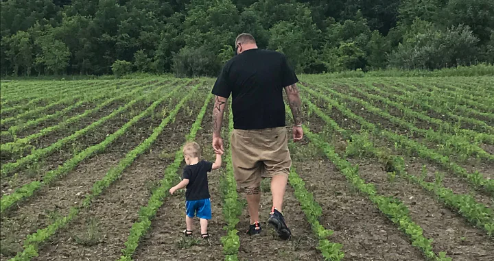 Alan Wilson walks through a field with his kid.