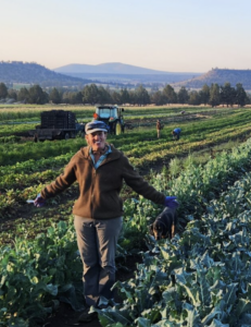 Sarahlee Lawrence, Rainshadow Organics (Oregon) Sarahlee Lawrence of Rainshadow Organics farm in Oregon standing in a vegetable field smiling with arms stretched out.