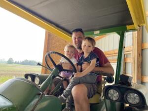 Alan Wilson poses on a tractor with his children.