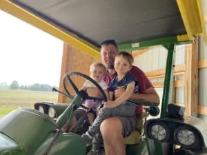 Alan Wilson poses on a tractor with his children.