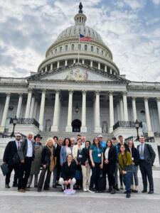 A group of people smiling outside the US Capitol Building.